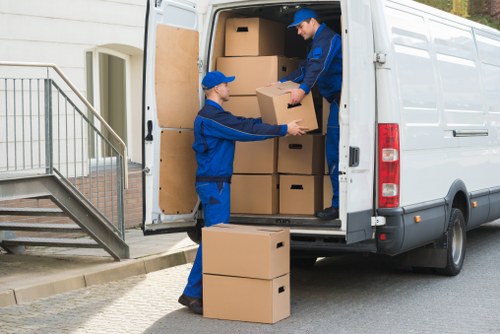 Movers handling boxes and furniture in a Wimbledon flat stairwell